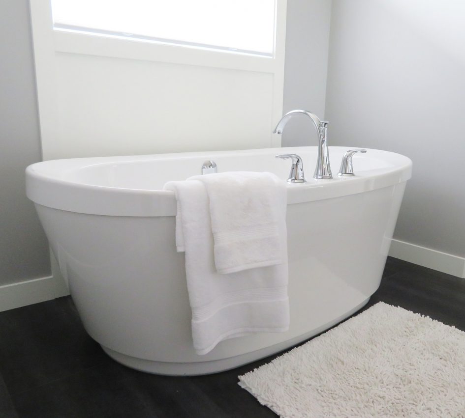 單體浴缸放置在黑色磁磚地板浴室掛著浴巾