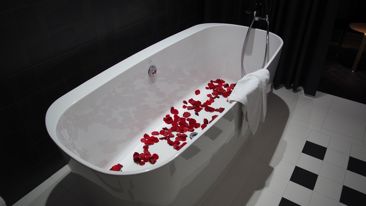 紅色花瓣灑佈在白色獨立浴缸底部