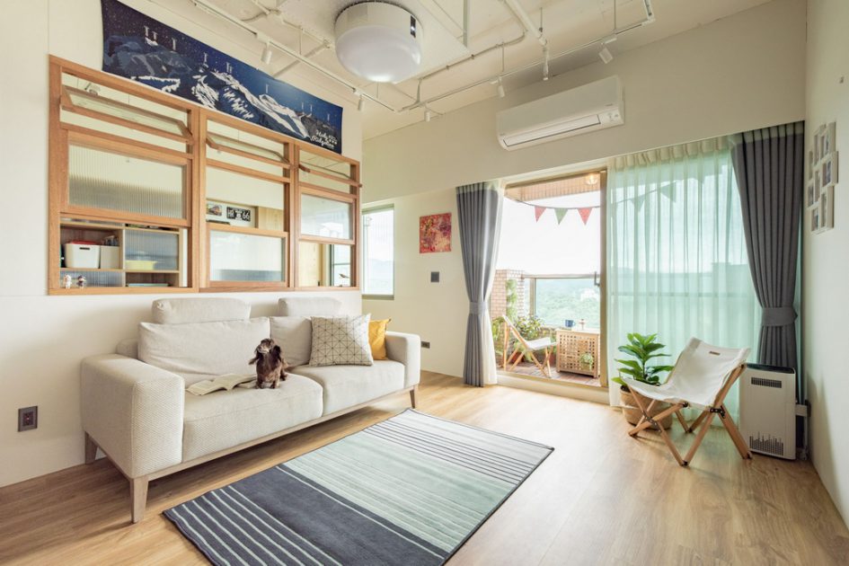 面向落地窗的客廳與白色布沙發、淺木色地板、小灰白雙色地毯